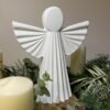 Ángel de la Guarda blanco entre velas y ramas de Navidad, foto real