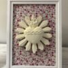 Cuadro del Sagrado Corazón de Jesús en relieve con tela flores multicolor visto de cerca sobre un mueble