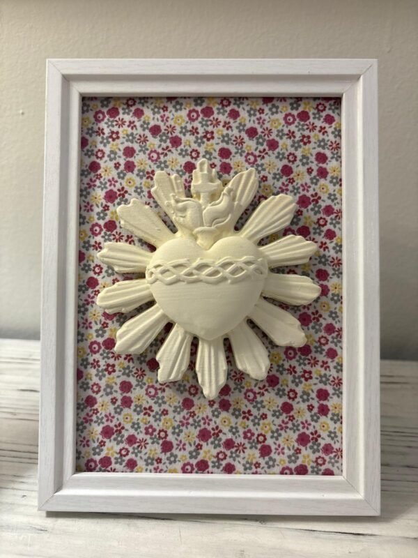 Cuadro del Sagrado Corazón de Jesús en relieve con tela flores multicolor visto de cerca sobre un mueble