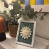 Cuadro del Sagrado Corazón de Jesús en relieve con tela flores verdes sobre el mueble del recibidor