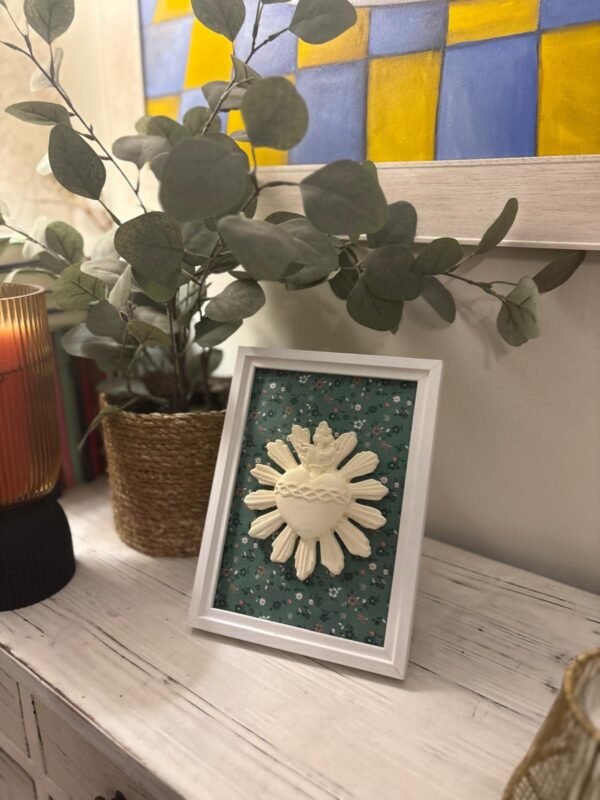 Cuadro del Sagrado Corazón de Jesús en relieve con tela flores verdes sobre el mueble del recibidor