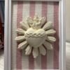 Cuadro del Sagrado Corazón de Jesús en relieve con tela rayas rosa apoyado de pie sobre un mueble