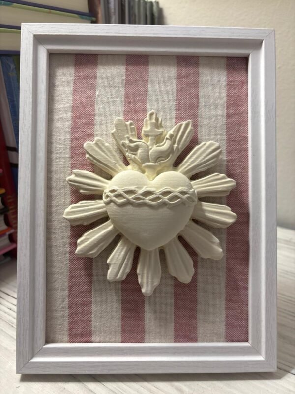Cuadro del Sagrado Corazón de Jesús en relieve con tela rayas rosa apoyado de pie sobre un mueble