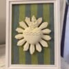 Cuadro del Sagrado Corazón de Jesús en relieve con tela rayas verde y azul apoyado de pie sobre un mueble