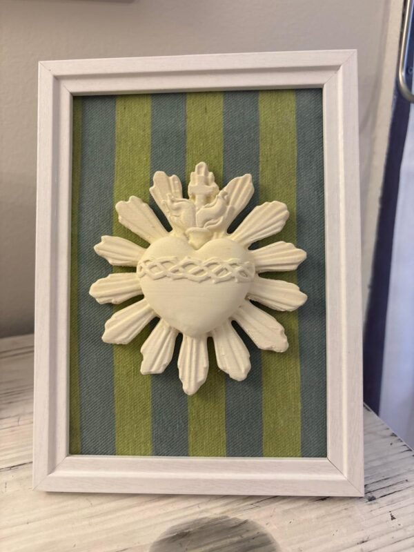 Cuadro del Sagrado Corazón de Jesús en relieve con tela rayas verde y azul apoyado de pie sobre un mueble