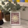 Cuadro del Sagrado Corazón de Jesús en relieve con tela vichy burdeos sobre el mueble del recibidor