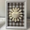 Cuadro del Sagrado Corazón de Jesús en relieve con tela vichy marrón apoyado de pie sobre un mueble