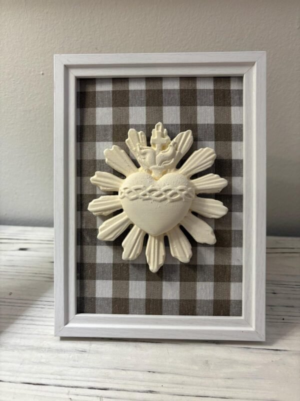 Cuadro del Sagrado Corazón de Jesús en relieve con tela vichy marrón apoyado de pie sobre un mueble