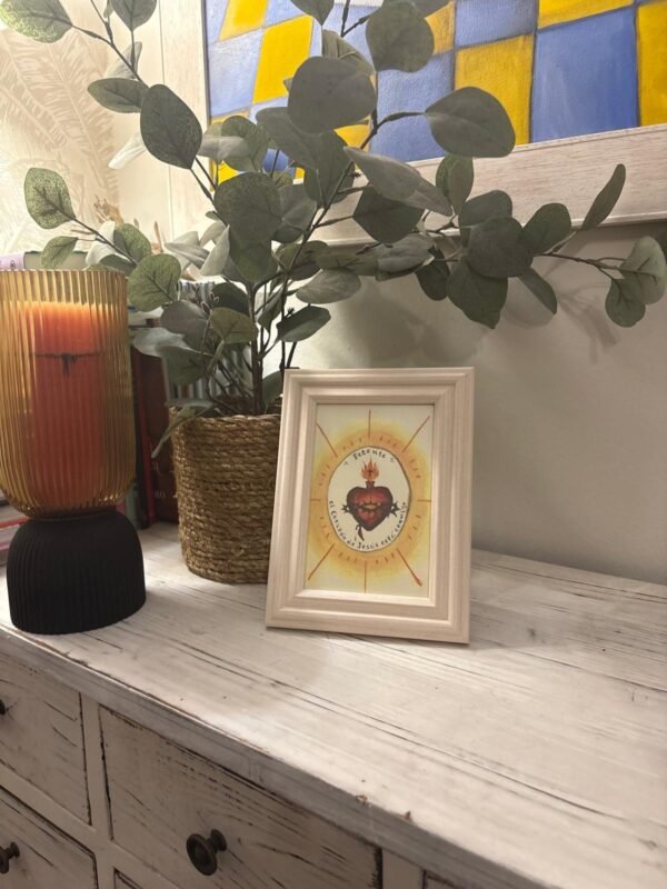 Detente del Sagrado Corazón de Jesús con marco madera clara junto a la entrada de casa