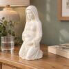 Figura de la Virgen de la dulce espera de 25 cm sobre una cómoda de madera